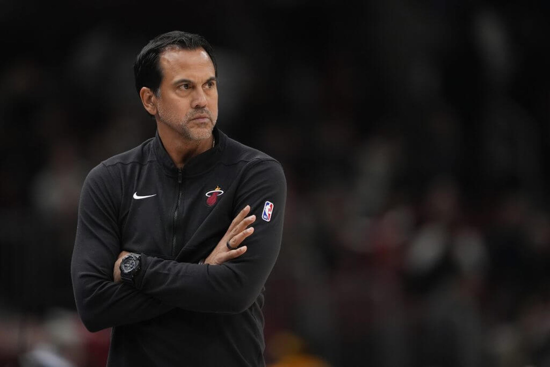 Miami Heat coach Erik Spoelstra crosses his arms and looks on at the court during a game.