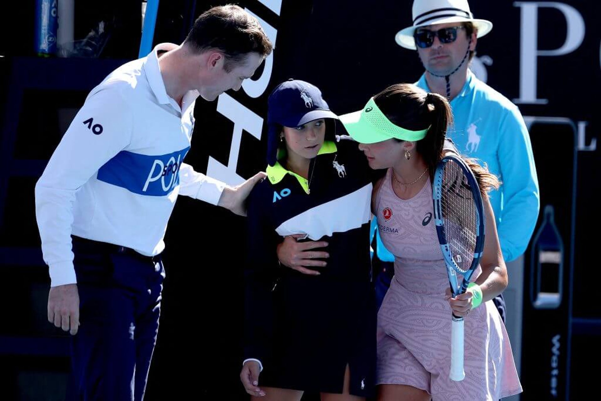 A tennis umpire (left) and Zeynep Sönmez (right) help a ball kid who had collapsed to stand up.