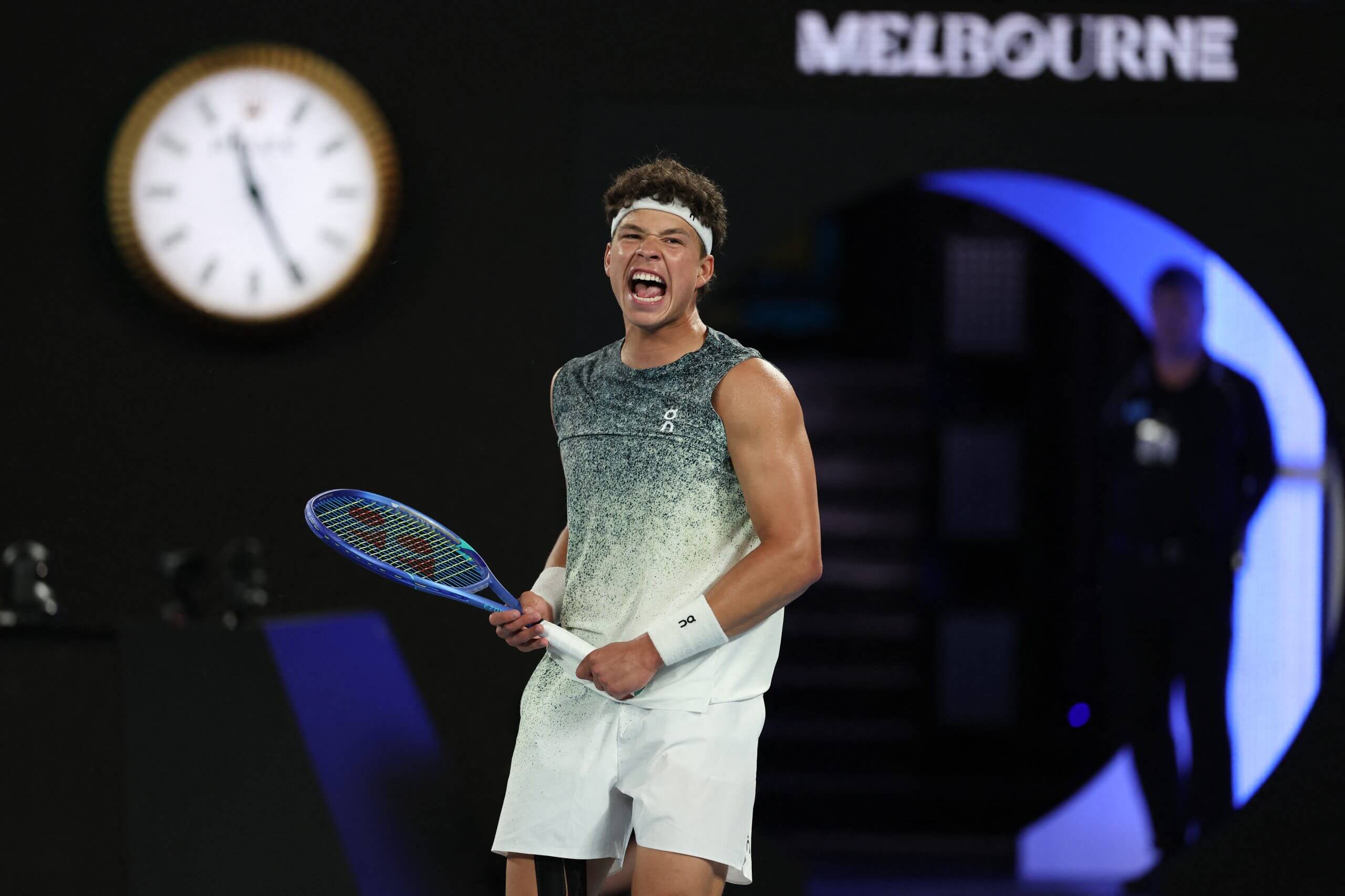 Ben Shelton roars in celebration in front of a clock and crescent-moon cut-out.